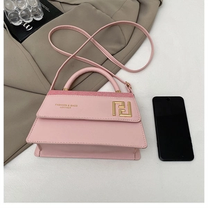 Détail du sac à main en cuir rose avec ferrures dorées et bandoulière en cuir amovible