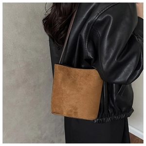 Detail of vintage brown suede bucket bag worn by model over a black leather jacket