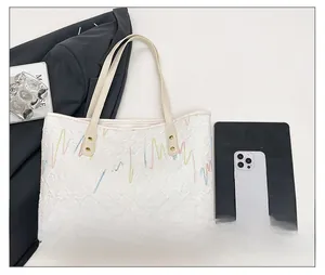 Detail of white tote bag featuring colorful wavy embroidery and brand name plaque