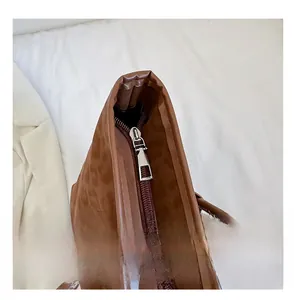 Close-up of smooth metal zipper and precision stitching on a brown suede tote bag