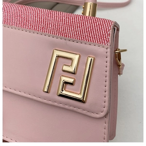 Détail du sac à main en cuir rose avec tissu rayé et finitions en métal doré