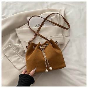 Close-up of brown suede bucket bag featuring metal chain drawstring and pearl charms
