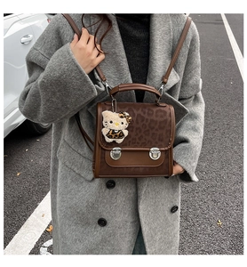 Détail d'un sac à main imprimé léopard avec boucles métalliques et pendentif en peluche