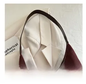 Detail of dark caramel suede tote bag with smooth leather strap on a chic blazer