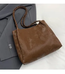 Detail of the brown vintage tote bag showing braided shoulder straps and matte leather
