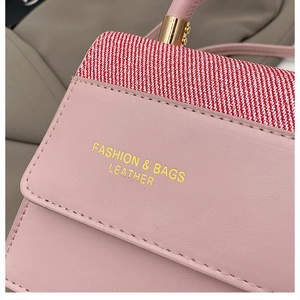 Gros plan d'un sac à main en cuir rose avec bordure en tissu rayé et lettrage doré