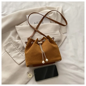 Detail of a brown suede bucket bag with pearl drawstring and golden metal chain