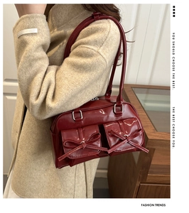 Close-up of a burgundy patent leather shoulder bag with chic bow pockets and silver hardware