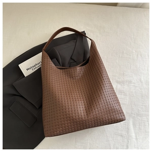 Détail de la texture en cuir tressé marron d'un grand sac à main porté épaule