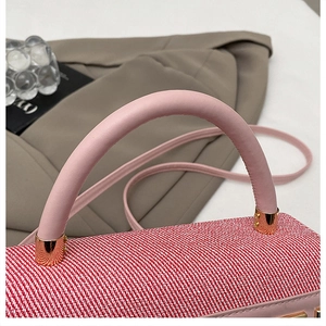 Gros plan sur le tissu tissé rouge et blanc et les détails métalliques dorés du sac à main