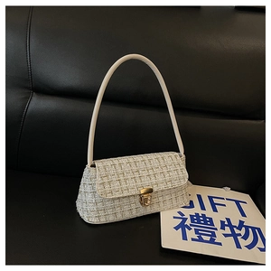 Dettaglio della trama in tweed della borsa con chiusura dorata e manico bianco rigido