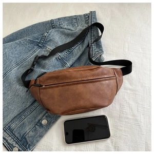 Brown PU leather crossbody bag size comparison with a smartphone and denim jacket