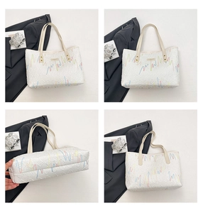 Close-up of white tote bag with letter embossing and colorful embroidery on the surface
