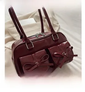 Macro shot of burgundy patent leather bag with bow pockets and silver metal zippers