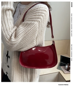 Borsa baguette in vernice rossa abbinata a cardigan beige per un look retrò ed elegante