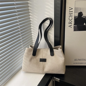 Minimalist beige canvas tote bag with black leather straps and premium texture details