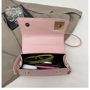 Vue de dessus d'un sac bandoulière rose ouvert montrant le rangement pour lunettes et écouteurs