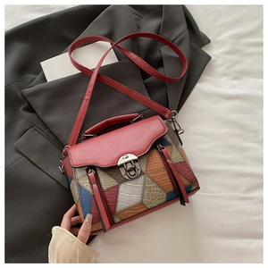 Detail of color-block patchwork leather bag with vintage metal lock on grey blazer