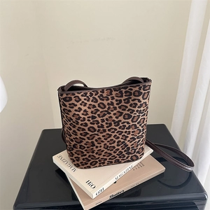 Trendy leopard print bucket bag with long shoulder strap displayed on magazines
