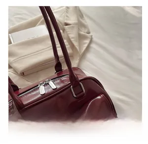 Close-up of sleek burgundy leather handbag featuring dual silver zippers and fine stitching