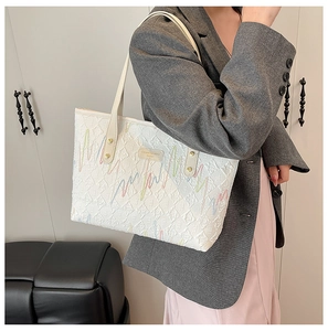 Detail of white quilted tote bag with colorful wave embroidery and gold rivet handles