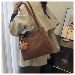 Brown matte leather tote bag detail with braided strap and cute plush bear charm