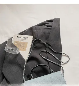 Close-up of light blue quilted chain bag placed on a grey blazer in a French retro style