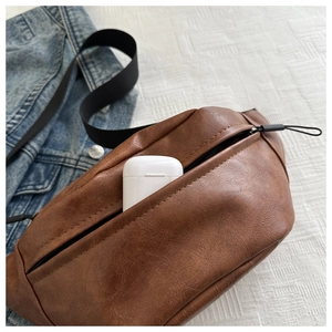 Close-up of brown PU leather chest bag with zipper and earphone storage capacity