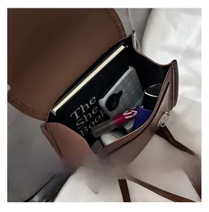 Capacité intérieure du mini sac en cuir marron montrant livres et produits cosmétiques