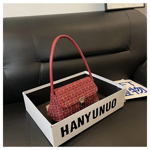 Dettaglio borsa in tweed rosso con elegante fibbia dorata su scatola display