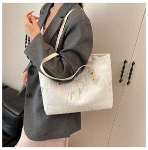 Close-up of the quilted texture and colorful wave embroidery on this cream tote bag