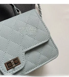 Detail of grey-blue quilted leather bag with metallic twist lock and chain strap