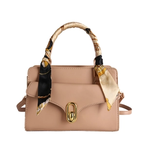 Pale pink leather handbag with gold U-shaped lock and silk scarf handle decoration
