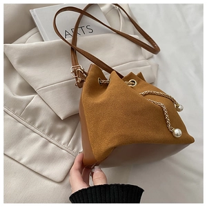 Detail of brown bucket bag showing suede stitching and pearl chain drawstring closure