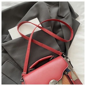 Macro detail of red and multi-color patchwork leather crossbody bag on grey suit fabric