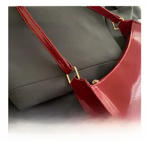 Close-up of golden square metal buckle on red patent leather shoulder bag