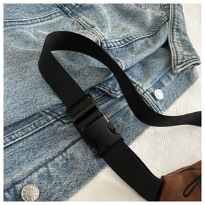 Macro detail of brown leather bag with adjustable black nylon strap and matte plastic buckle