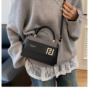 Détail du sac bandoulière avec rabat gris et boucle dorée porté par un mannequin chic