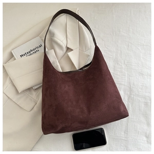 Macro view of burgundy suede hobo bag with brown leather strap on blazer background