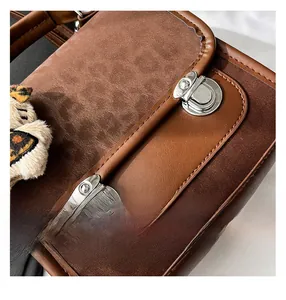 Détails du sac à main en daim marron avec garniture en cuir et breloque en peluche léopard