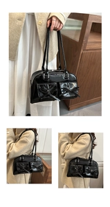 Detail of glossy black tote bag with dual front pockets and elegant bow decoration