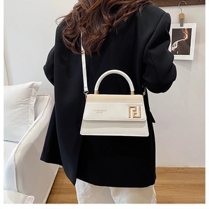 Détail d'un sac bandoulière en cuir blanc avec boucle dorée et logo imprimé élégant