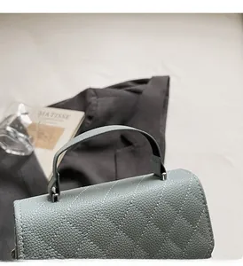 Detail of grey-green quilted handbag with litchi grain texture and sturdy top handle