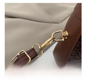 Gros plan du crochet doré et de la bandoulière en cuir marron du sac croissant