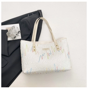 Detail view of large white tote bag featuring vibrant embroidery and dual thin straps
