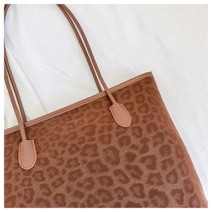 Detail of leopard print faux fur texture and smooth leather strap on a tote bag