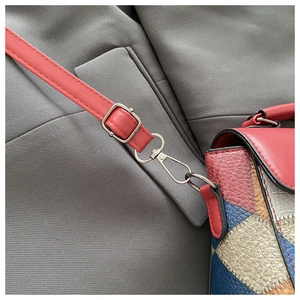 Detail of adjustable red leather strap with silver metal hook on a colorful square bag