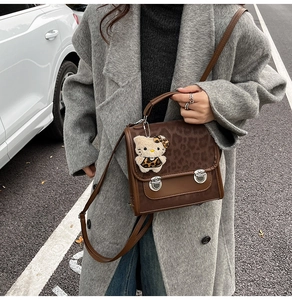 Gros plan du sac à main léopard avec fermoirs argentés et pendentif en peluche doux