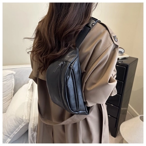 Close-up of black crossbody chest bag with adjustable strap and multiple zipper pockets