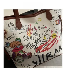 Detail of white lychee leather bucket bag with colorful bear graffiti and brown handle